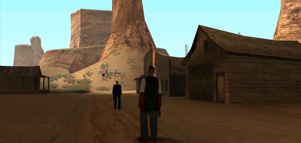 Two players standing one in front of the other in the Ghost Town holding a Desert Eagle.